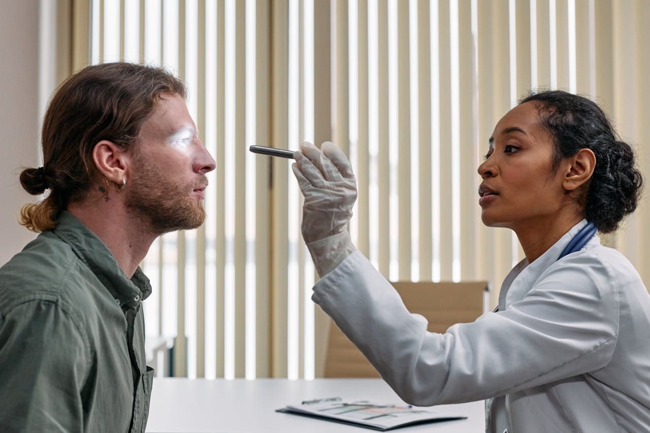urgent care doctor checking patient's eye with flashlight